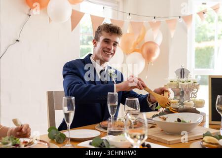 Marié souriant en costume servant de la nourriture à la réception de mariage dans un décor festif Banque D'Images