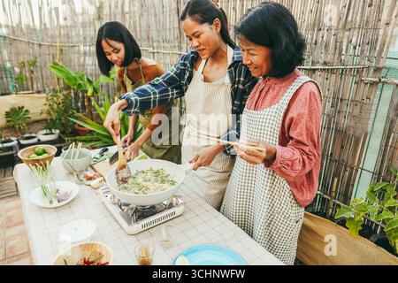 Cuisine asiatique famille cuisinant le dîner thaïlandais ensemble à la maison patio extérieur - style de vie et concept de nourriture - accent principal sur le visage de fille centre Banque D'Images