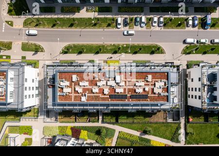 Vue aérienne de haut en bas de l'immeuble d'appartements moderne avec terrasse verdoyante sur le toit et panneaux solaires pour un concept de logement écologique Banque D'Images