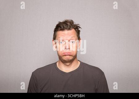 Homme très frustré avec des expressions faciales dans la photo de studio avec fond gris, homme d'âge moyen frustré européen, espace de copie Banque D'Images