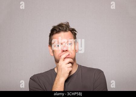 Homme très frustré avec des expressions faciales dans la photo de studio avec fond gris, homme d'âge moyen frustré européen, espace de copie Banque D'Images