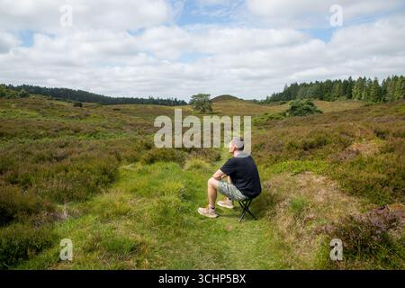 l'homme seul est assis tranquillement sur un tabouret dans le heatland dans la lumière du soleil se reposant et pensant, bien-être en plein air, l'homme seul dans la nature pensant Banque D'Images