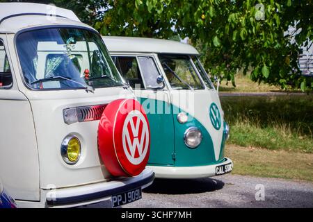 Deux camionnettes Volkswagen Vintage garées sous les arbres par une journée ensoleillée, présentant un design classique et un attrait rétro Banque D'Images