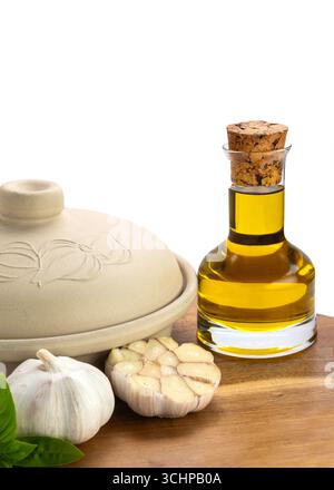 Bulbes d'ail frais, huile d'olive dans une bouteille en verre, et un pot en argile sur une surface en bois, symbolisant la cuisine naturelle et la cuisine méditerranéenne. dos blanc Banque D'Images