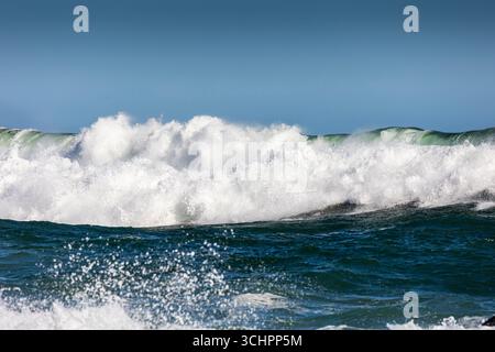 Puissant brise-vague océanique avec mousse d'eau vive et éclaboussure dans la mer féroce sous ciel bleu clair paysage marin Banque D'Images
