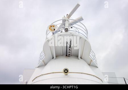 Ferry radar et haut-parleurs du dessous Landskrona Suède // LANDSKRONA, Suède — le radar et les haut-parleurs sont visibles sur le pont supérieur d'un ferry. Le ferry est blanc et a un design moderne, avec diverses antennes et équipements de communication montés sur sa structure. Le ciel au-dessus est couvert, fournissant un arrière-plan neutre pour la technologie maritime. Le ferry opère dans les eaux près de Landskrona, une ville située dans la région de Skåne, dans le sud de la Suède. Banque D'Images
