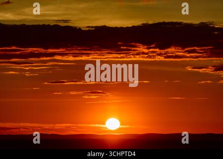 Lever de soleil sur la côte suédoise Kattegat Strömstad Suède // Strömstad, Suède — Un lever de soleil vibrant peint le ciel sur la mer du Kattegat, vu de l'eau près de Strömstad. Le soleil, un orbe lumineux, émerge au-dessus d'un horizon silhouetté de la côte suédoise. Les guirlandes de nuages saisissent les teintes dorées et oranges de l'aube, créant un spectacle spectaculaire. Strömstad est une ville côtière située dans le comté de Västra Götaland en Suède. Le Kattegat est un détroit séparant le Danemark et la Suède, reliant la mer Baltique à la mer du Nord. Banque D'Images