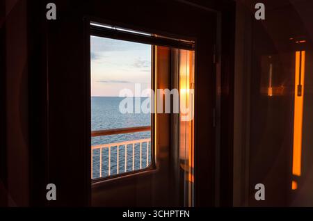 Copenhague à Oslo Ferry au lever du soleil Skagerrak Suède // Strömstad, Suède — la vue depuis une fenêtre sur un ferry voyageant entre Copenhague et Oslo au lever du soleil sur le détroit de Skagerrak. La ligne de ferry relie la capitale du Danemark à la capitale de la Norvège, en passant par le Skagerrak, la partie nord-est de la mer du Nord, qui sépare la Norvège du Danemark et de la côte ouest de la Suède. Ce voyage offre des vues panoramiques sur la côte scandinave et la mer. Banque D'Images