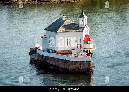 Phare Dyna Fyr Oslofjord Norvège | LYSAKER, Norvège — Dyna Fyr, construit en 1874, s’élève depuis sa plateforme dans l’intérieur de l’Oslofjord au large de la côte de Lysaker en Akershus. La structure blanche avec son lanterne rouge distinctive a été réaffectée de phare actif à lieu de réunion privé, apportant une touche d’excentricité tranquille à cette partie du fjord. Sa forme compacte et sa position isolée sur les eaux ouvertes en font l’un des repères les plus reconnaissables entre le détroit de Drøbak et le port d’Oslo. Banque D'Images