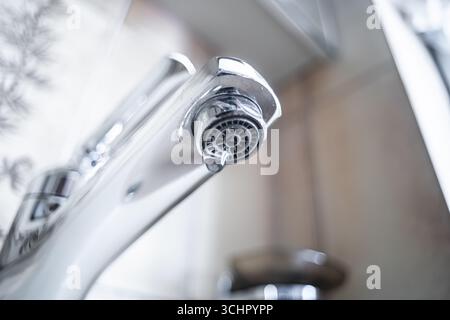Robinet goutte à goutte avec des gouttelettes d'eau à l'intérieur de la salle de bains de l'appartement. Macro, gros plan, vue rapprochée, faible profondeur de champ, personne Banque D'Images
