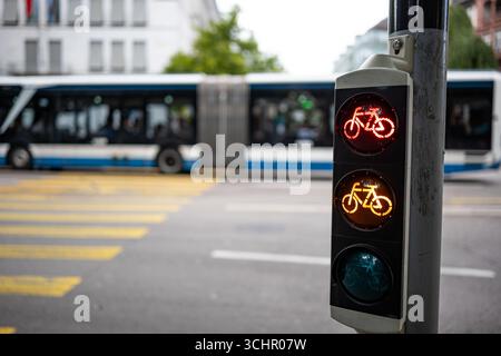 Feu de circulation pour vélo à côté du passage piéton, rouge et jaune. Gros plan, prise de vue grand angle, faible profondeur de champ, arrière-plan flou et bu Banque D'Images