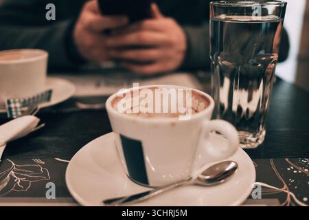 Un gros plan de deux tasses à café vides sur une soucoupe avec cuillère, servi à une table de café confortable. Rendez-vous à la cafétéria. Banque D'Images