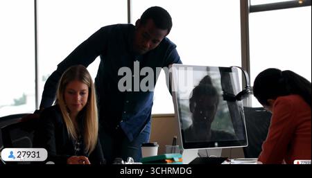 Examen des documents, collègues penchés sur le bureau dans un bureau moderne, avec moniteur et tasses à café Banque D'Images