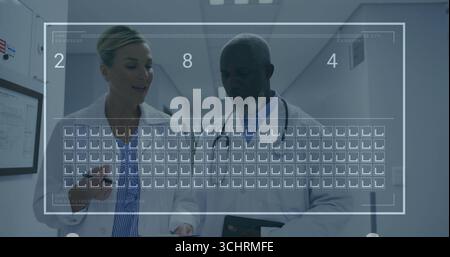 Médecins marcheurs discutant des données avec tablette et presse-papiers dans le couloir de l'hôpital, avec stéthoscope Banque D'Images