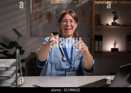 Infirmière fatiguée et stressée travaillant pendant des heures à l'expertise médicale dans le bureau de l'hôpital, dactylographiant le rapport du patient sur ordinateur. Assistant examinant Medi Banque D'Images