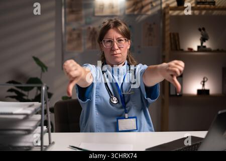 Infirmière fatiguée et stressée travaillant pendant des heures à l'expertise médicale dans le bureau de l'hôpital, dactylographiant le rapport du patient sur ordinateur. Assistant examinant Medi Banque D'Images
