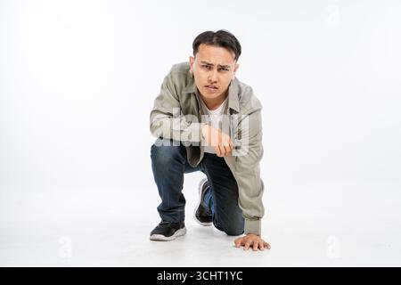 Un jeune homme élégant pose dans la mode urbaine avec une posture accroupie dynamique Banque D'Images
