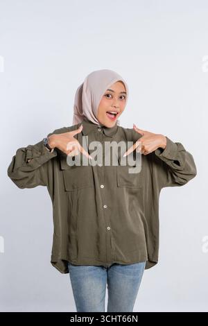 Joyeuse jeune femme pointant joyeusement sa tenue colorée avec un grand sourire Banque D'Images