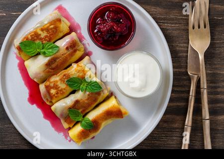Crêpes roulées frites farcies de fromage cottage et de cerise, dessert sucré sur assiette, gros plan, vue de dessus. Pâtisserie maison. Délicieux fast-food pour bre Banque D'Images