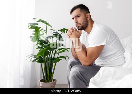 Pensif triste fatigué millénaire musculaire européen homme assis sur le lit souffrant seulement de dépression et de stress Banque D'Images