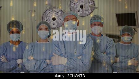 Équipe médicale debout portant des blouses bleues et des masques dans la salle d'opération avec superposition de monnaie numérique Banque D'Images