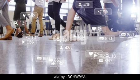 Les jambes des employés de bureau se déplaçant à travers le sol dans un bureau moderne, avec des icônes sociales flottantes Banque D'Images
