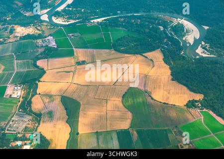 Le patchwork de champs récoltés rencontre des terres agricoles verdoyantes, bordées par une rivière sinueuse et une forêt dense. Beauté rurale aérienne. À partir des champs de la ferme au-dessus, créez vib Banque D'Images