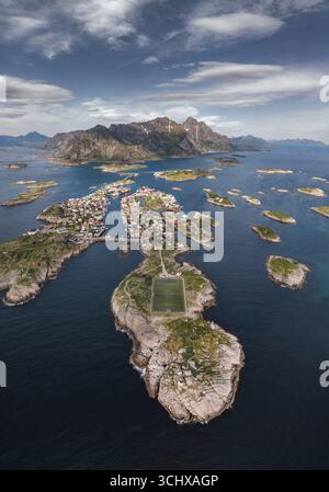 Vue aérienne d'un terrain de football sur une petite île au milieu de la vaste mer bleue profonde, entourée d'îlots rocheux et de montagnes lointaines, Srvgen, Nordland, Banque D'Images