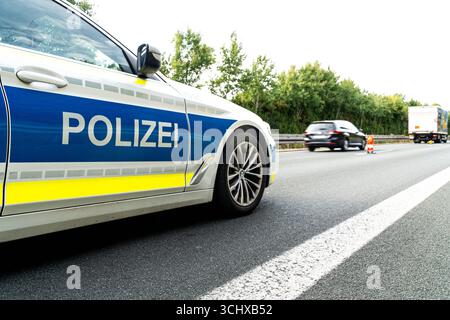 Landkreis Osnabrück, Deutschland 27. Août 2025 : Im Bild : Polizeifahrzeug auf der Autobahn, das die rechte Fahrspur absperrt. Der blau-gelb markierte Streifenwagen steht auf der rechten Fahrbahnseite, während der Verkehr über die verbleibenden Spuren vorbeigeleitet wird. IM Hintergrund sind Pkw, LKW und Warnbaken zur zusätzlichen Absicherung des Einsatzortes zu sehen. Typische Szene eines Polizeieinsatzes auf der Autobahn zur Verkehrsregelung und Gewährleistung der Sicherheit. Niedersachsen *** District de Osnabrück, Allemagne 27 août 2025 dans l'image véhicule de police sur l'autoroute bloquant Banque D'Images