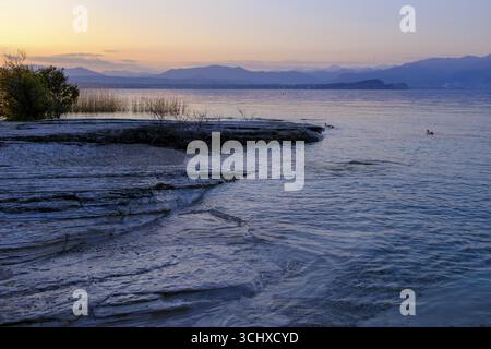 Coucher de soleil à Lido delle Grotte, Jamaica Beach, Sirmione sur le lac de Garde, Vénétie, Vénétie, Italie Banque D'Images