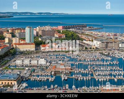 Vue aérienne d'un port animé rempli d'innombrables voiliers blancs contrastant avec la mer bleue profonde, encadrée par l'architecture de la ville, Trieste, Frioul-Vénétie Julienne, Italie. Banque D'Images