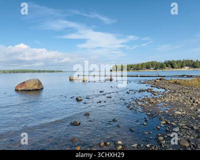 Vue panoramique sur un rivage rocheux et l'eau calme sous un ciel bleu. Banque D'Images