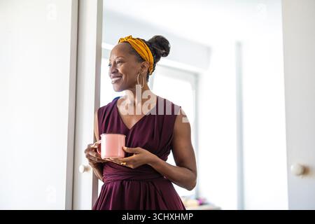 Portrait de femme d'affaires souriante tenant une tasse de café dans le bureau Banque D'Images