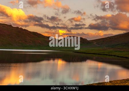 Vue sur le lac placide reflétant le coucher de soleil ardent et les montagnes escarpées, un paysage serein peinture de la grandeur de la nature, Deosai National Park, Gilgit Ba Banque D'Images