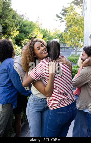 Jeunes amis divers s'embrassant sur le patio, célébrant de joyeuses retrouvailles dans le jardin ensoleillé Banque D'Images