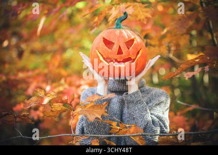 femme tenant une citrouille d'halloween devant son visage Banque D'Images