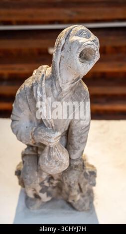 Gros plan sur une ancienne statue en pierre représentant un mendiant tenant un sac et criant Banque D'Images