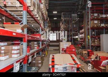 L'intérieur d'un entrepôt animé présente de grandes étagères bordées de boîtes et de produits. La lumière du soleil coule à travers une fenêtre, mettant en évidence l'organisation Banque D'Images