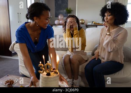 Diverses amies féminines célébrant l'anniversaire avec un gâteau et des bougies, partageant des moments joyeux à la maison Banque D'Images