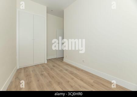 Chambre principale non décorée avec penderie luxueuse en bois blanc, portes moulées classiques et quincaillerie ancienne en laiton Banque D'Images