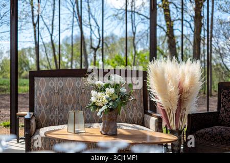 Le coin salon moderne présente un arrangement floral élégant et des accents décoratifs, offrant une ambiance confortable et accueillante parfaite pour les célébrations et Banque D'Images