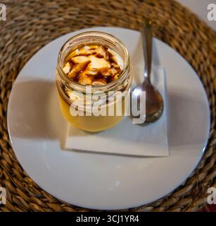 Setenil de las Bodegas, Espagne - 11 mars 2025 : vue rapprochée d'un dessert espagnol traditionnel servi dans un bocal en verre, garni de crème fouettée et Banque D'Images