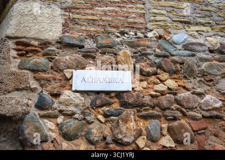 La Alhambra, Espagne - 12 mars 2025 : gros plan d'un mur de pierre texturé avec une variété de roches et de briques colorées avec un panneau blanc indiquant Alha Banque D'Images