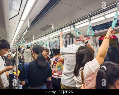 Un train de métro bondé avec des passagers debout tenant sur les mains courantes pendant un trajet très fréquenté dans un environnement urbain singapour MRT asie Banque D'Images