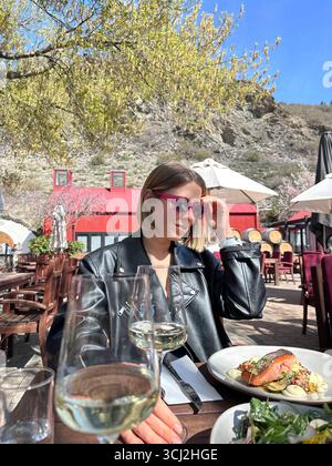 Une femme élégante profite du déjeuner avec un verre de vin dans un domaine viticole avec une vue pittoresque sur la terrasse Banque D'Images