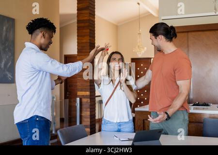 Amis célébrant le succès ensemble à la maison, souriant et passionnant autour de la tablette. Célébration, amitié, bonheur, High Five, technologie, intérieur Banque D'Images