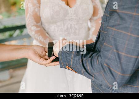 Mariée et mariée participent à un échange d'anneau sincère lors d'un mariage de jardin entouré par la nature. Banque D'Images