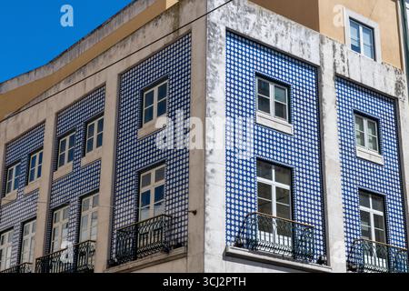Une photo focalisée du coin d’un bâtiment à Lisbonne, mettant en évidence sa façade recouverte de tuiles traditionnelles d’azulejo portugais. La vitrine photographique Banque D'Images