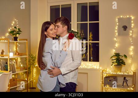 Couple dans la soirée debout serrant dans la chambre avec guirlandes Banque D'Images