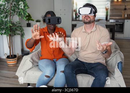 Couple explorant la réalité virtuelle en utilisant des casques vr à la maison Banque D'Images